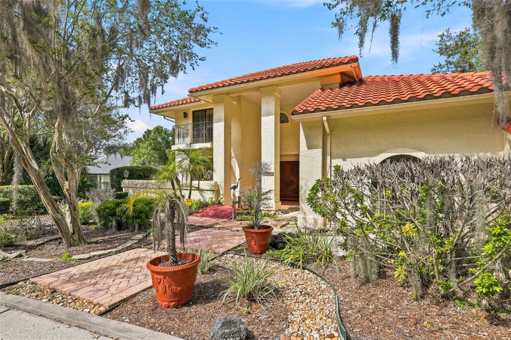 A two-story stucco house with a red tile roof and a brick walkway entrance — 5359 SADDLEBROOK WAY, WESLEY CHAPEL, FL
