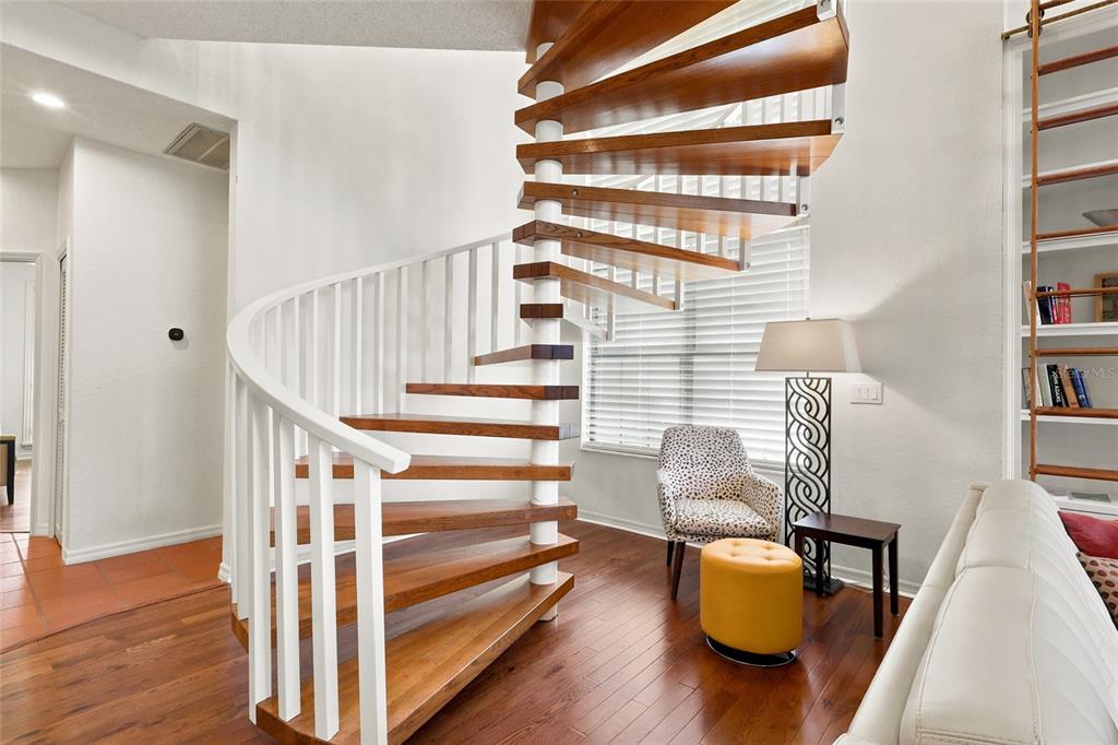 A spiral staircase with wooden treads and white railings stands in a living room — 5359 SADDLEBROOK WAY, WESLEY CHAPEL, FL