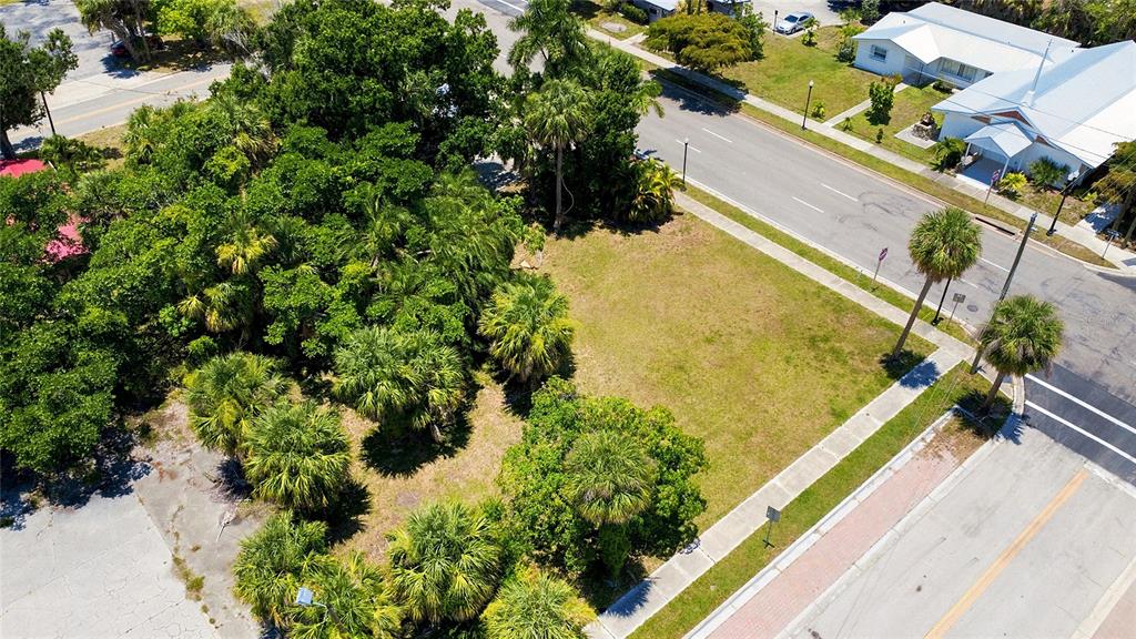 An aerial view shows a vacant, grassy corner lot surrounded by trees and paved roads — 261 E OLYMPIA AVENUE, PUNTA GORDA, FL