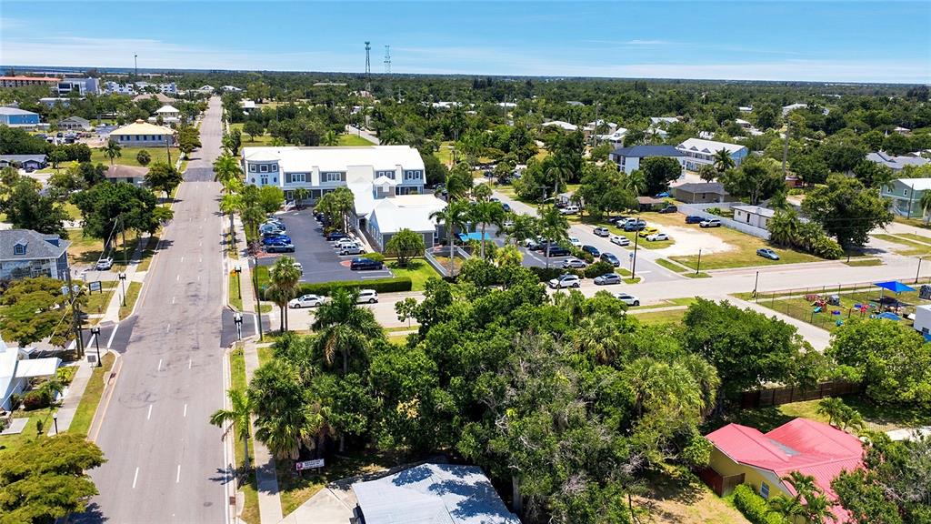 An aerial view shows a multi-story commercial building, surrounding parking lots, and nearby residential streets — 261 E OLYMPIA AVENUE, PUNTA GORDA, FL