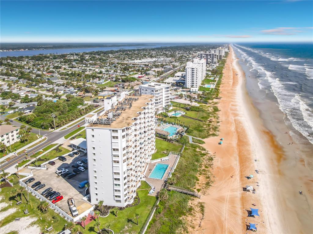 An aerial view of a beachfront high-rise condominium complex with a pool and parking lot — 1051 OCEAN SHORE BOULEVARD UNIT 304, ORMOND BEACH, FL