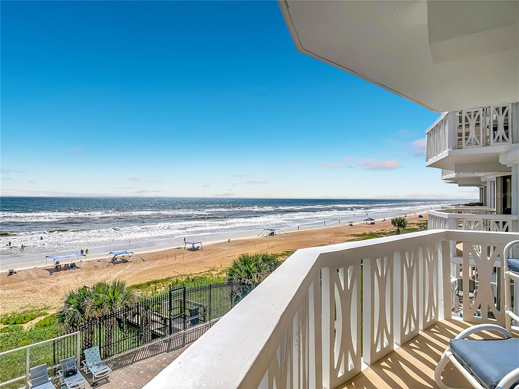 A balcony overlooks a sandy beach and the ocean with white railings and lounge chairs — 1051 OCEAN SHORE BOULEVARD UNIT 304, ORMOND BEACH, FL