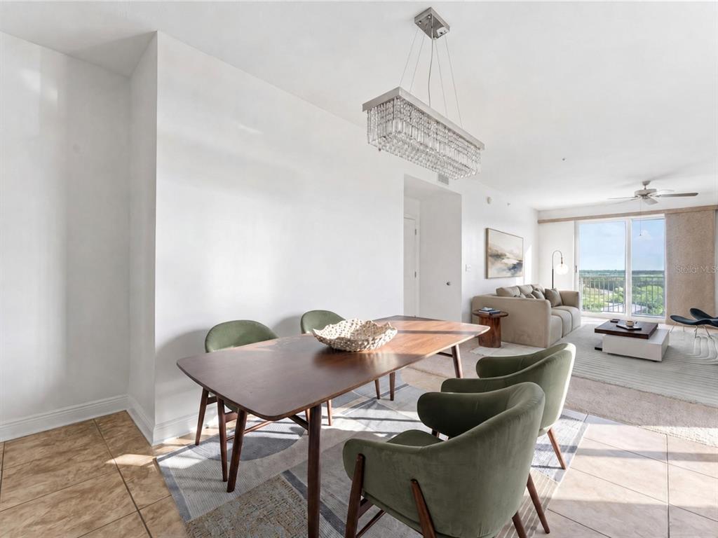 A dining area with a wooden table, green chairs, and a crystal chandelier near a living room — 628 CLEVELAND STREET UNIT 1211, CLEARWATER, FL