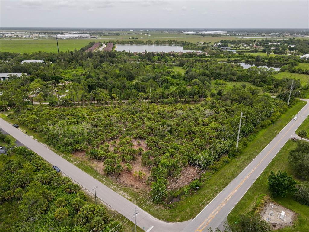 An aerial view shows a vacant, wooded corner lot bordered by two paved roads — 25471 TECHNOLOGY BOULEVARD, PUNTA GORDA, FL
