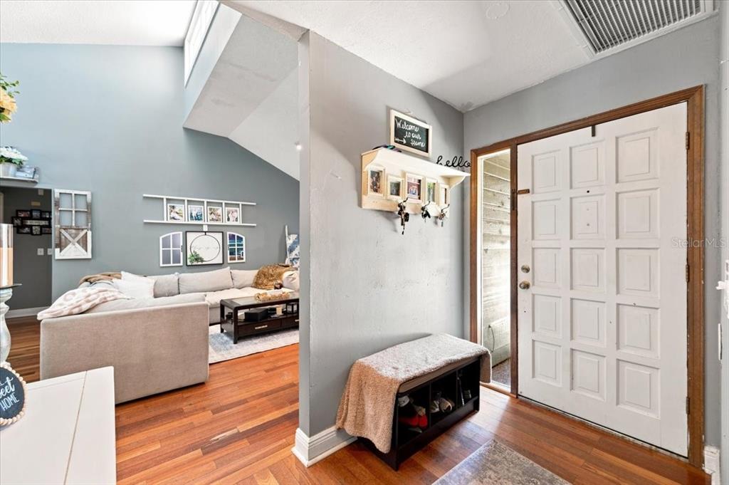 An entryway with a white door, a shoe bench, and a view into a living room — 4475 OLD COLONY ROAD, MULBERRY, FL