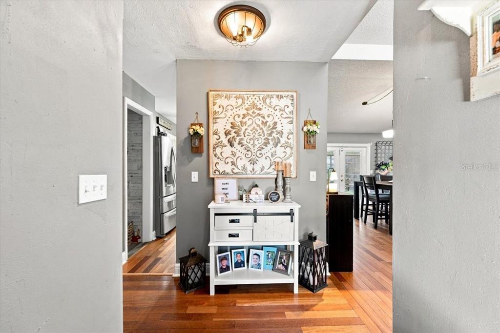 A hallway features a white console table with a decorative wall hanging and hardwood floors — 4475 OLD COLONY ROAD, MULBERRY, FL