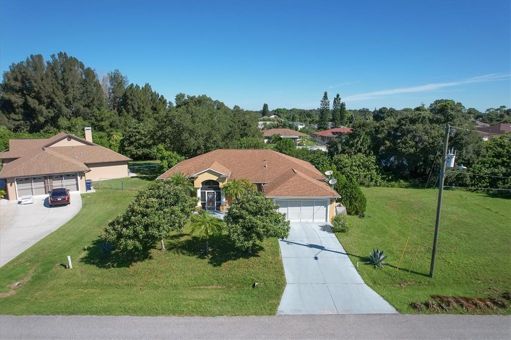 An aerial view shows a single-story house with a brown roof and a concrete driveway — 12004 SARTO LANE, NORTH PORT, FL