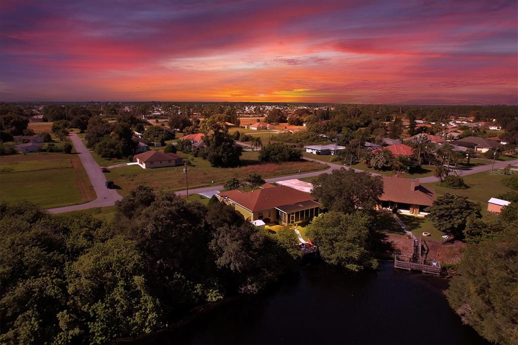 An aerial view of a waterfront house with a dock at sunset — 12004 SARTO LANE, NORTH PORT, FL