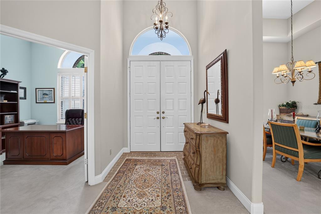 An entryway features a double door, a patterned rug, a wooden chest, and a chandelier — 7759 SE 12TH CIRCLE, OCALA, FL