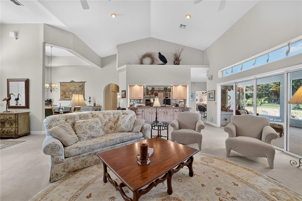 A living room features a vaulted ceiling, a floral sofa, two armchairs, and a wet bar — 7759 SE 12TH CIRCLE, OCALA, FL