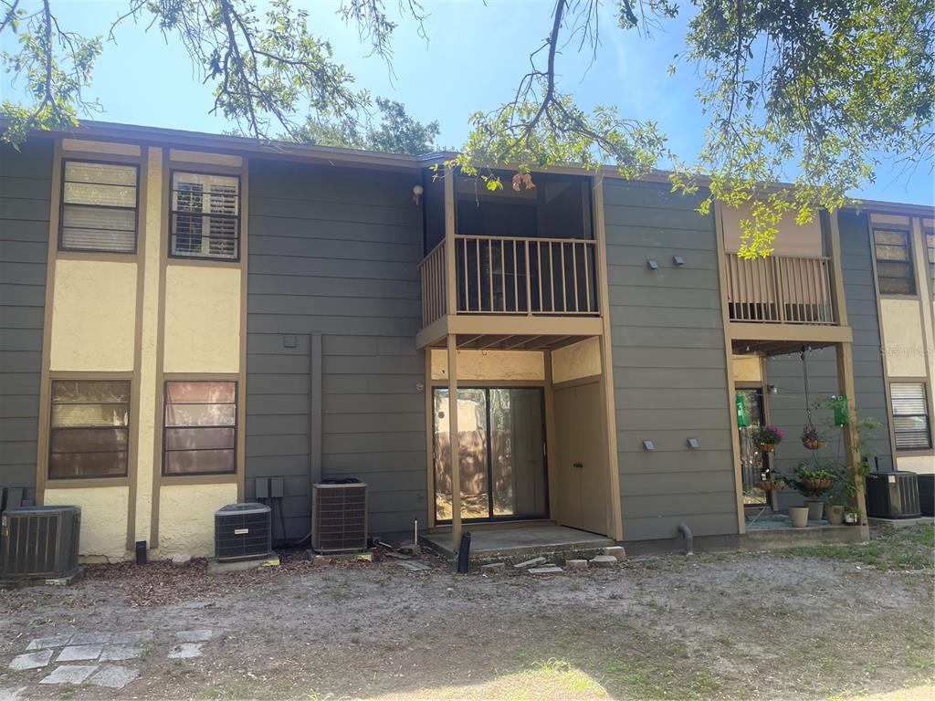 The exterior of a two-story apartment building features dark siding, balconies, and ground-level patios — 4809 S MOUND AVENUE UNIT 105, TAMPA, FL