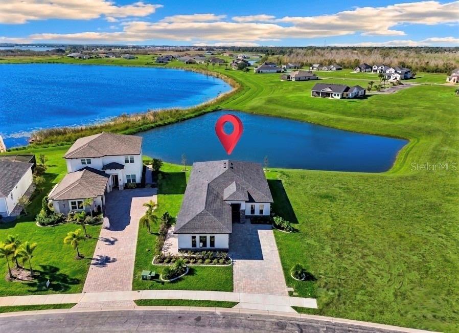An aerial view of a modern single-story house with a paver driveway and waterfront backyard — 224 VALENCIA RIDGE DRIVE, AUBURNDALE, FL