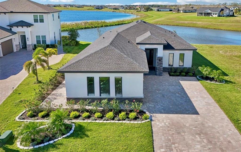 A modern single-story house with a paved driveway, stone accents, and a dark garage door — 224 VALENCIA RIDGE DRIVE, AUBURNDALE, FL