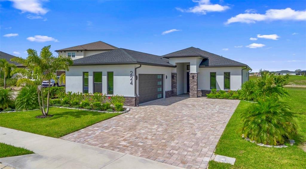 A modern single-story house with a stone-accented facade, a paved driveway, and a garage — 224 VALENCIA RIDGE DRIVE, AUBURNDALE, FL