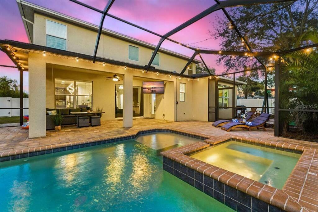 A screened-in patio features a swimming pool, a hot tub, and outdoor lounge furniture — 2930 W ROGERS AVENUE, TAMPA, FL