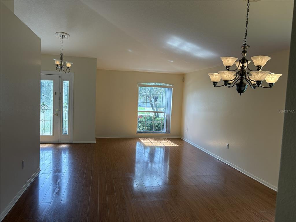 An empty living room features light-colored walls, wood-look flooring, vertical blinds, and a ceiling fan — 924 RIDGE HAVEN DRIVE, BRANDON, FL