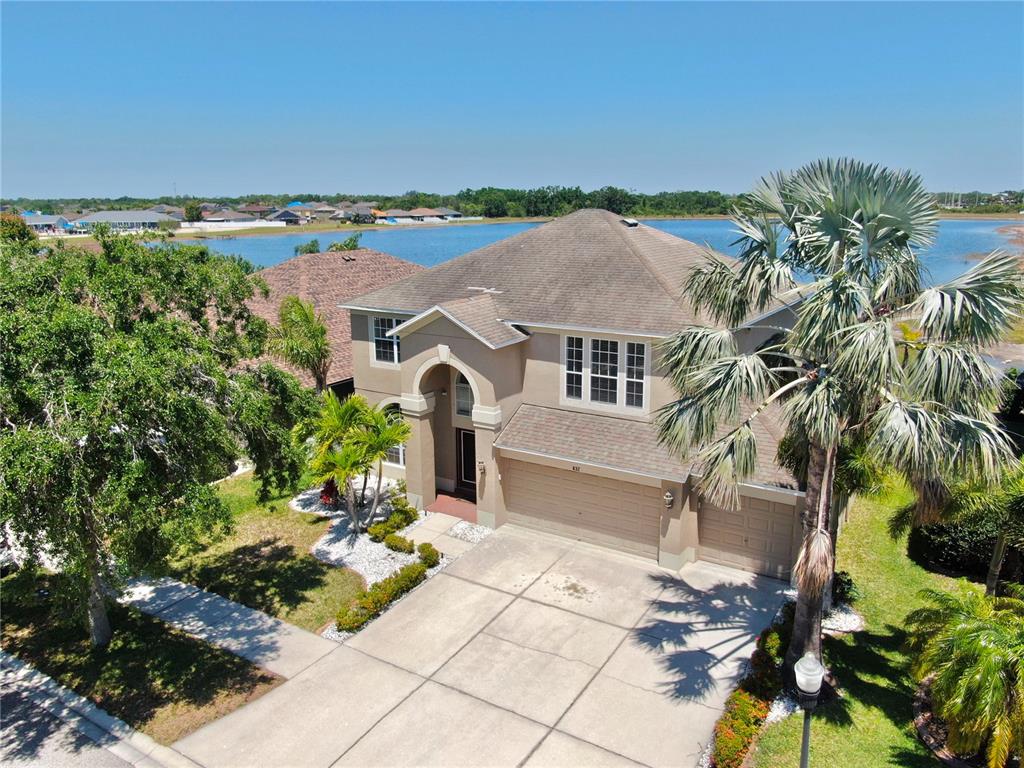 An aerial view of a two-story suburban house with a concrete driveway and lakefront backyard — 632 TANANA FALL DRIVE, RUSKIN, FL