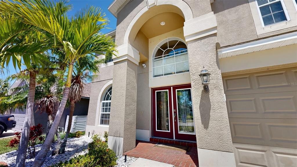 The exterior of a two-story house features a red double front door and palm trees — 632 TANANA FALL DRIVE, RUSKIN, FL