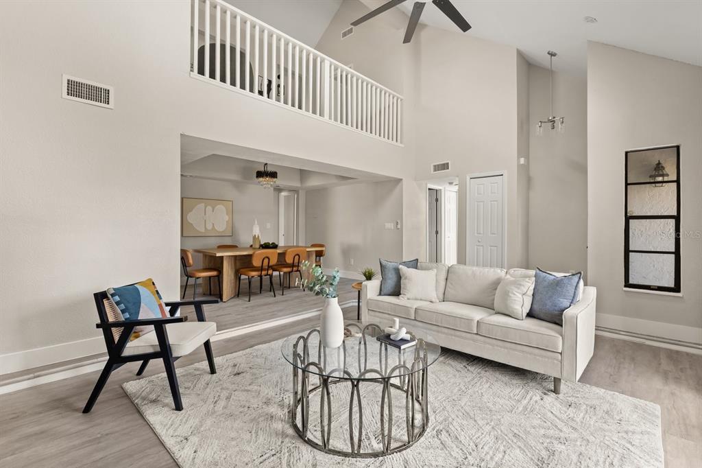 A living room with a vaulted ceiling, loft railing, and an adjacent dining area — 1540 STONE TRAIL, DELTONA, FL