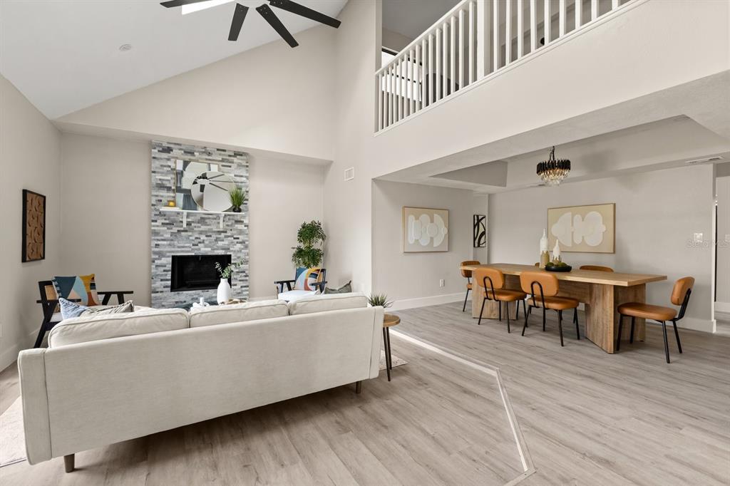 A living room with a stone fireplace and vaulted ceiling opens to a dining area — 1540 STONE TRAIL, DELTONA, FL
