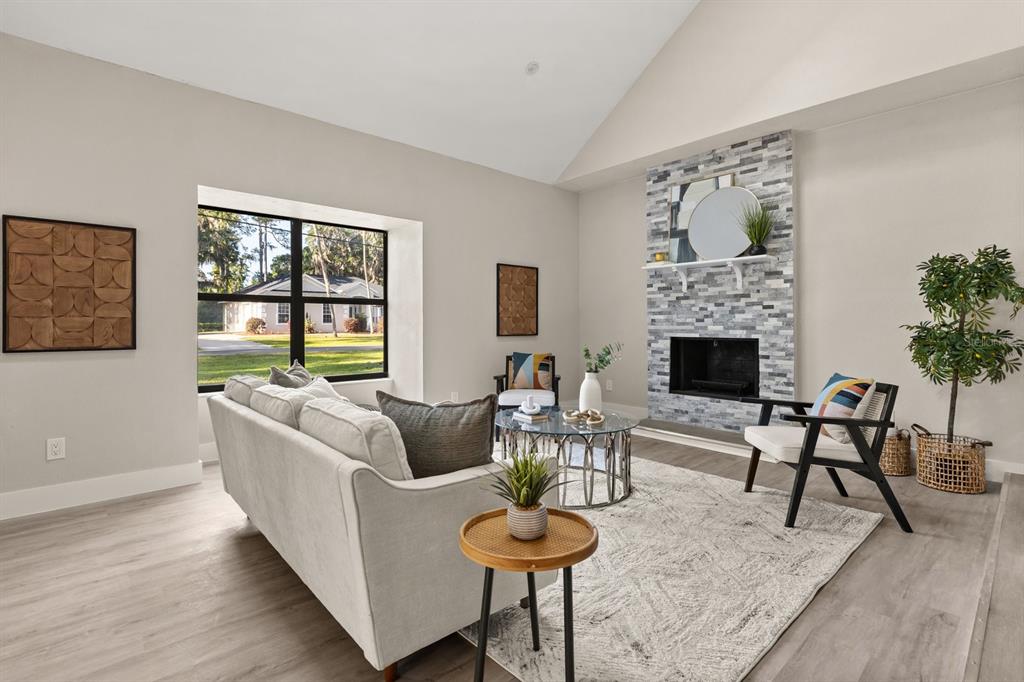 A living room features a vaulted ceiling, a stone fireplace, and a large window — 1540 STONE TRAIL, DELTONA, FL