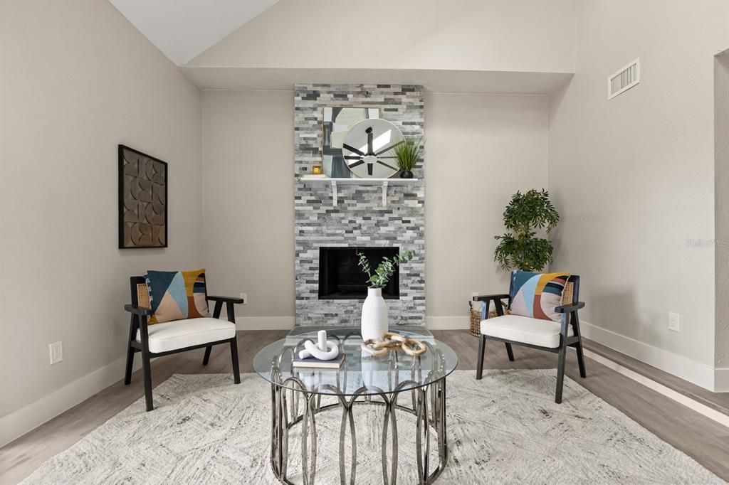 A living room features a stone fireplace, two armchairs, and a glass-topped coffee table — 1540 STONE TRAIL, DELTONA, FL
