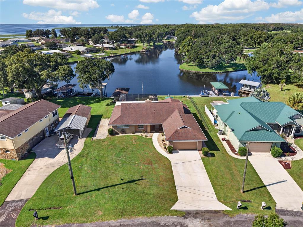 An aerial view shows a waterfront house with a brown roof and a concrete driveway — 3515 LITTLE LAKE DRIVE, SEBRING, FL