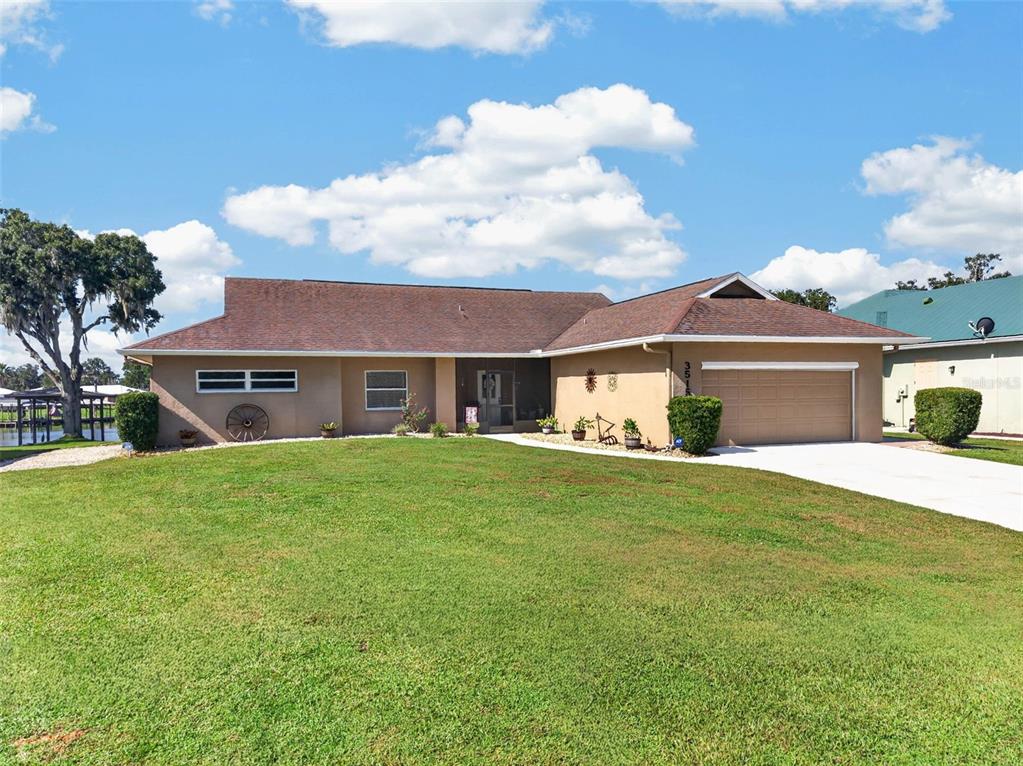 A single-story house with a brown roof, tan stucco exterior, and a two-car garage — 3515 LITTLE LAKE DRIVE, SEBRING, FL