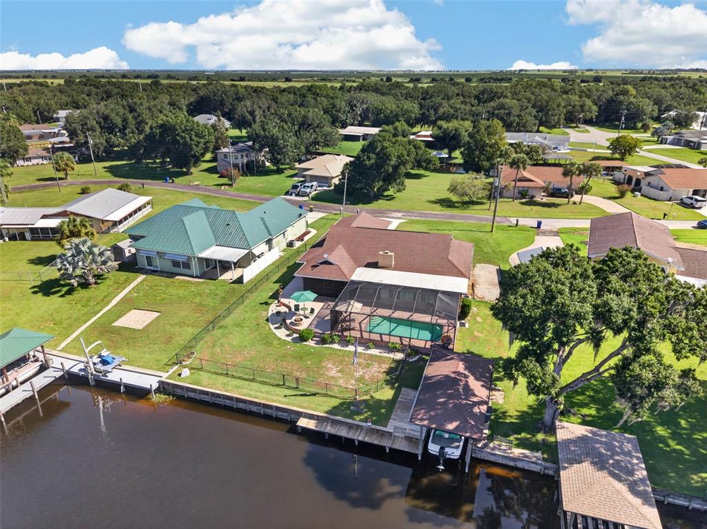 An aerial view shows two waterfront houses with pools, docks, and boat slips on a canal — 3515 LITTLE LAKE DRIVE, SEBRING, FL