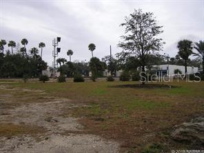 A vacant, grassy lot features scattered trees and a railroad crossing signal in the background — 0 S Dixie FREEWAY, NEW SMYRNA BEACH, FL