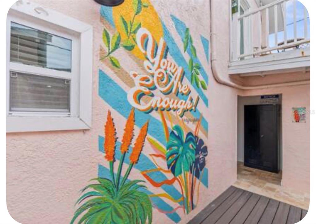 A dining area features a wooden table, light blue chairs, and a large tropical leaf mural — 106 E BAY DRIVE, TREASURE ISLAND, FL