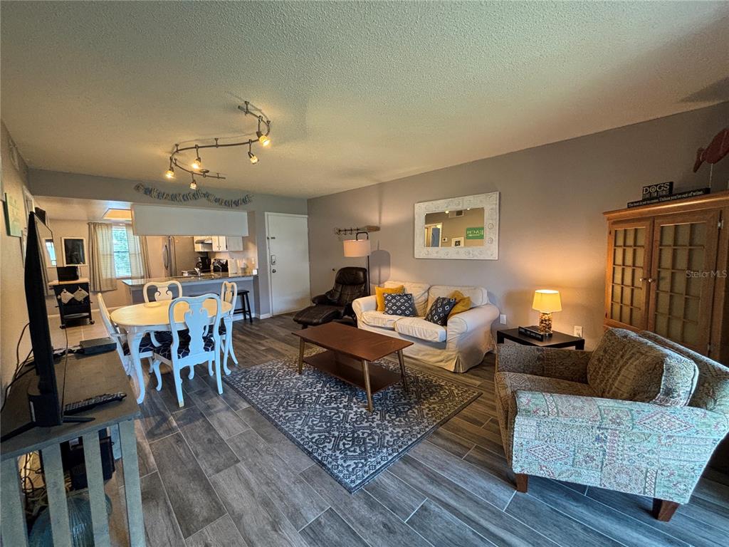 An open-concept living and dining area features wood-look tile flooring and a neutral color palette — 204 MEADOW LANE UNIT 204, OLDSMAR, FL
