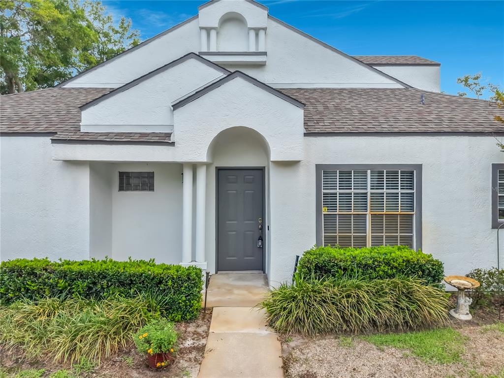 The exterior of a white stucco house features a gray front door and a walkway — 248 WIMBLEDON CIRCLE UNIT 248, LAKE MARY, FL