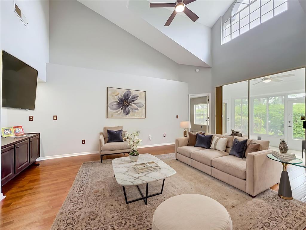 A living room features vaulted ceilings, hardwood floors, a marble coffee table, and a sofa — 248 WIMBLEDON CIRCLE UNIT 248, LAKE MARY, FL