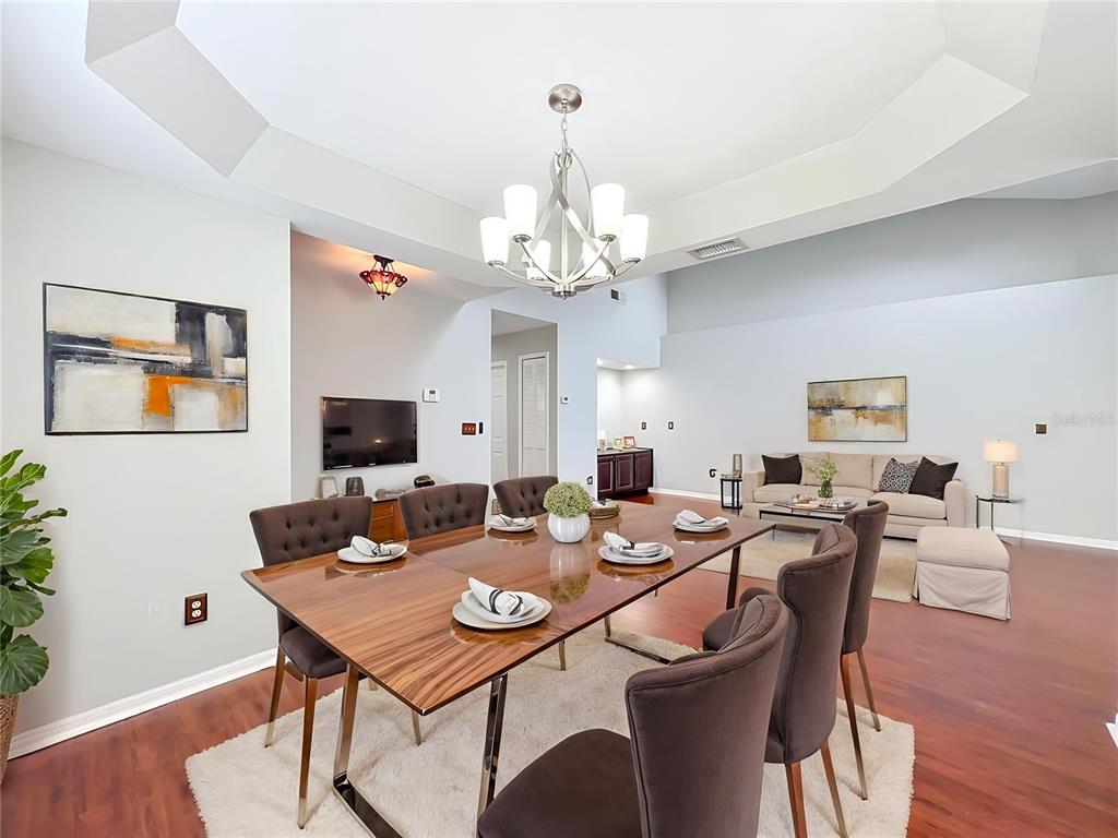 A dining room with a wooden table and chairs sits in front of a living area — 248 WIMBLEDON CIRCLE UNIT 248, LAKE MARY, FL