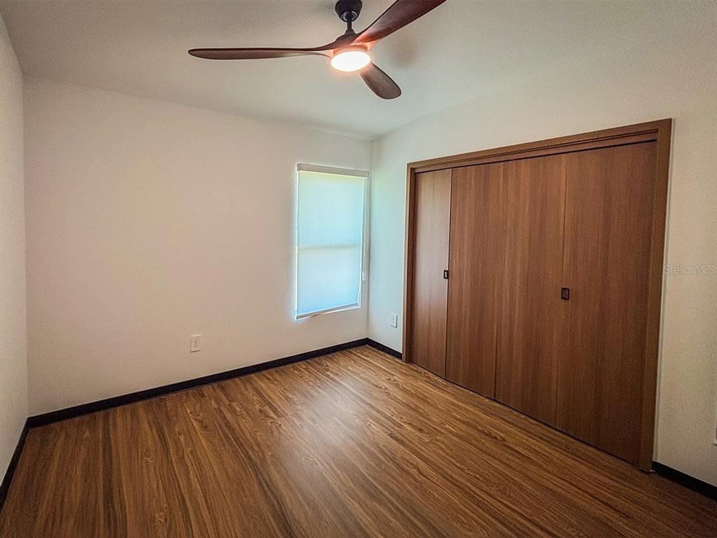 A kitchen features white cabinets, a stone-patterned countertop, and wood-paneled walls — 5620 VIRTUDES STREET, SEBRING, FL