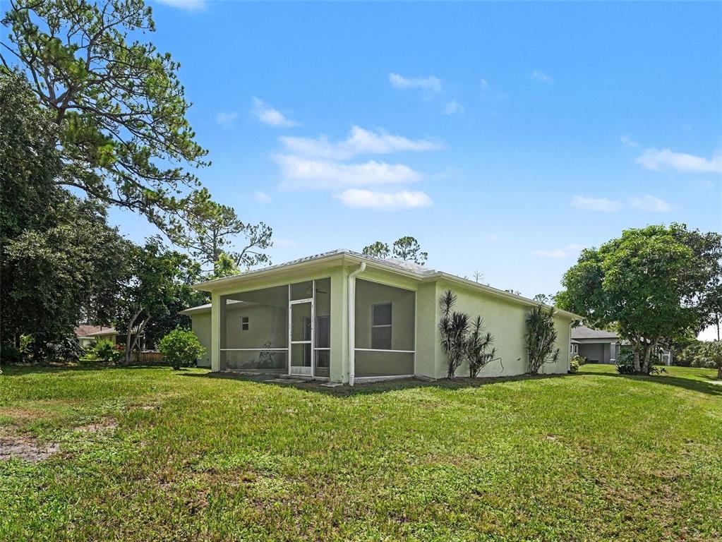 A light green house with a screened-in porch sits on a grassy lot — 4288 DUREVE AVENUE, NORTH PORT, FL