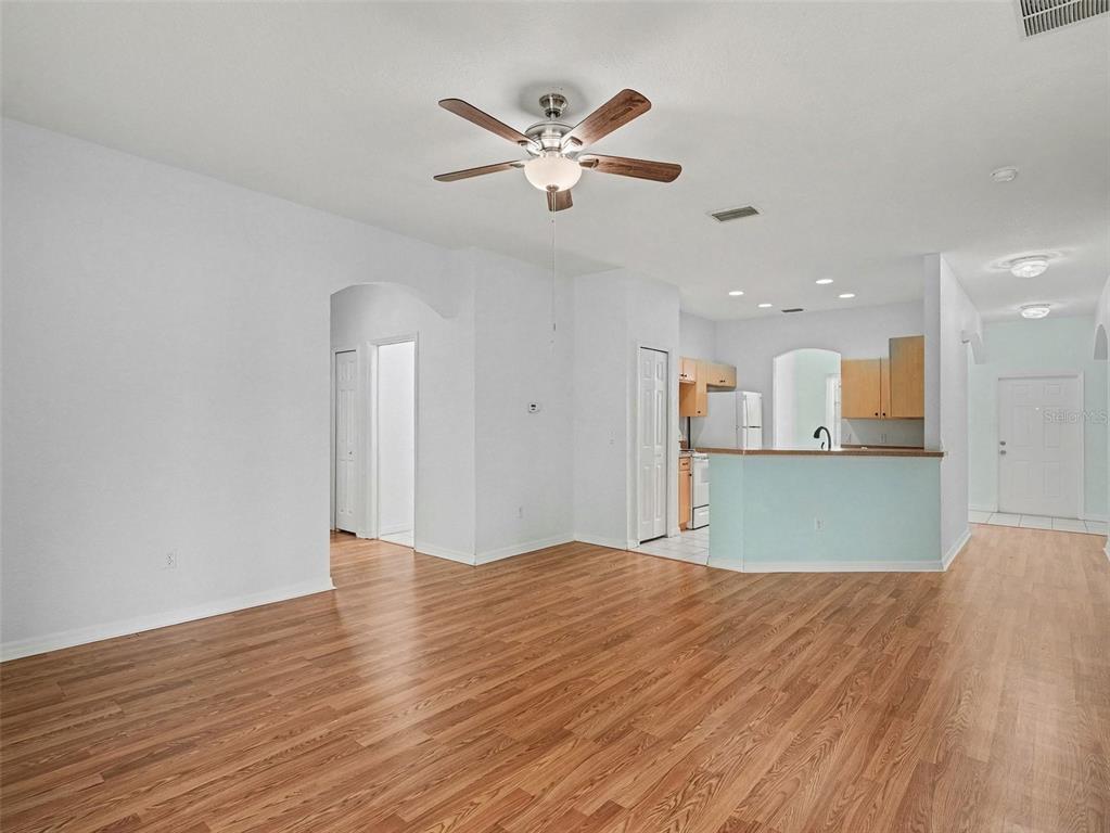 An open-concept living area features wood-look flooring, a ceiling fan, and an adjacent kitchen — 4288 DUREVE AVENUE, NORTH PORT, FL