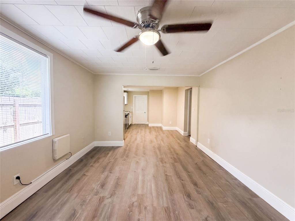 A living room with wood-look flooring, a ceiling fan, and an opening to a kitchen — 8103 N 18TH STREET, TAMPA, FL