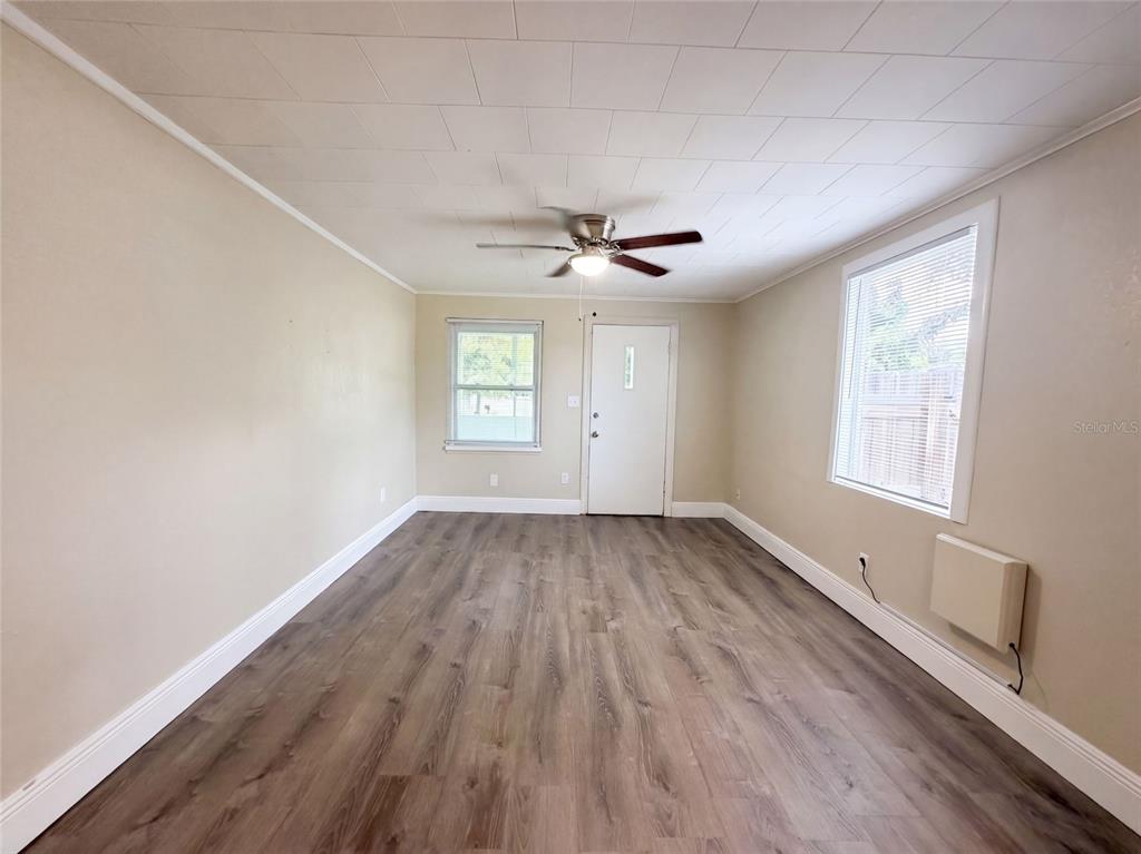 An empty room features light-colored walls, wood-look flooring, a ceiling fan, and two windows — 8103 N 18TH STREET, TAMPA, FL