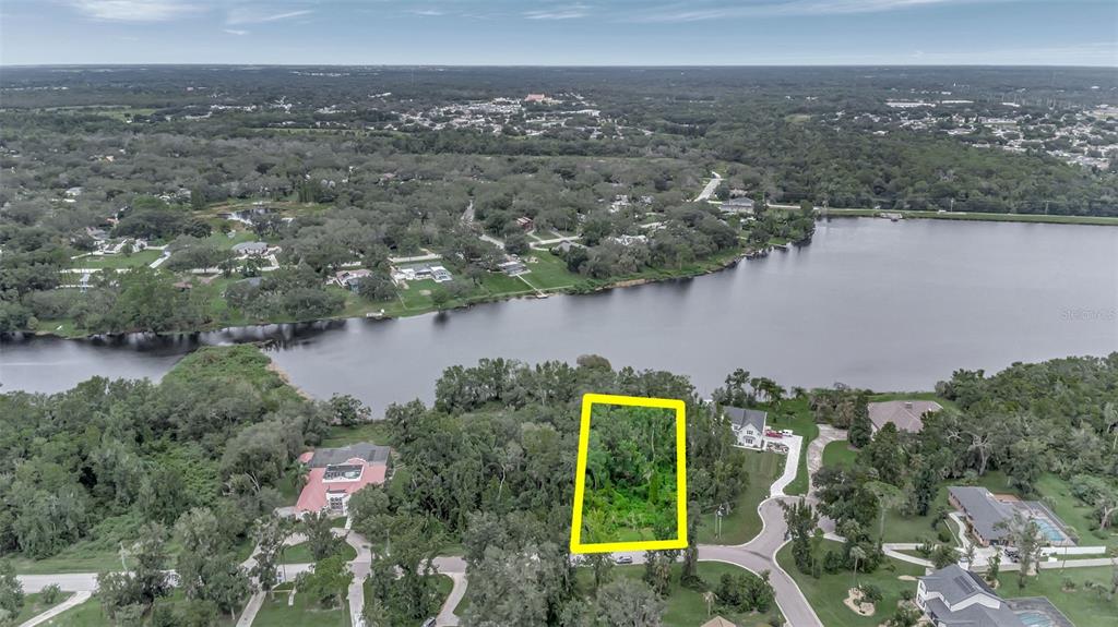An aerial view shows a vacant, tree-covered lot outlined in yellow near a lake — 12610 LAKE HILLS DRIVE, RIVERVIEW, FL