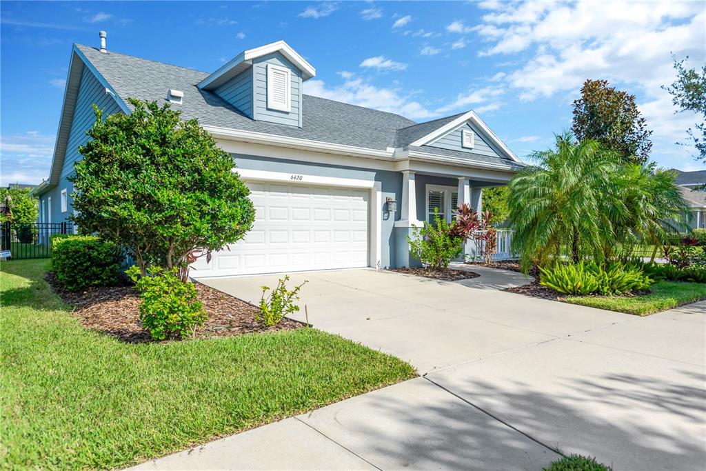 A blue house with a two-car garage, a dormer window, and a front porch — 6420 SEASOUND DRIVE, APOLLO BEACH, FL