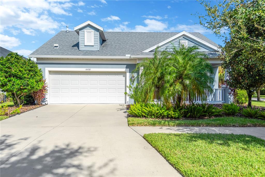 A single-story house with a white garage door, a front porch, and a dormer window — 6420 SEASOUND DRIVE, APOLLO BEACH, FL