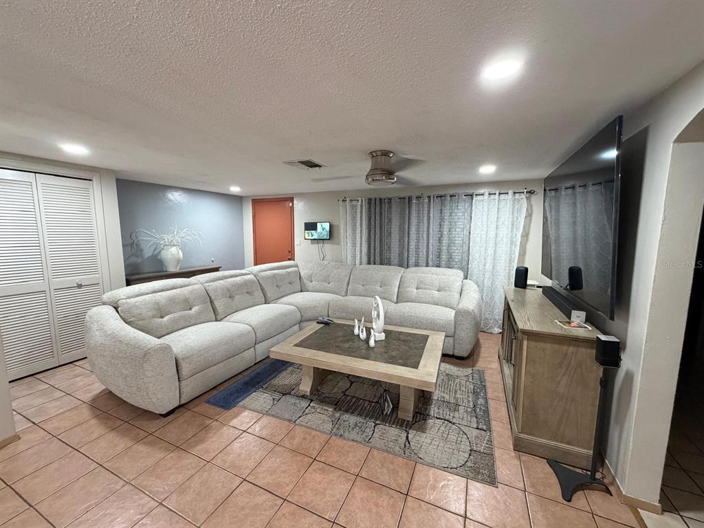 A living room features a large sectional sofa, a coffee table, and a wall-mounted television — 9236 GRAY FOX, PORT RICHEY, FL