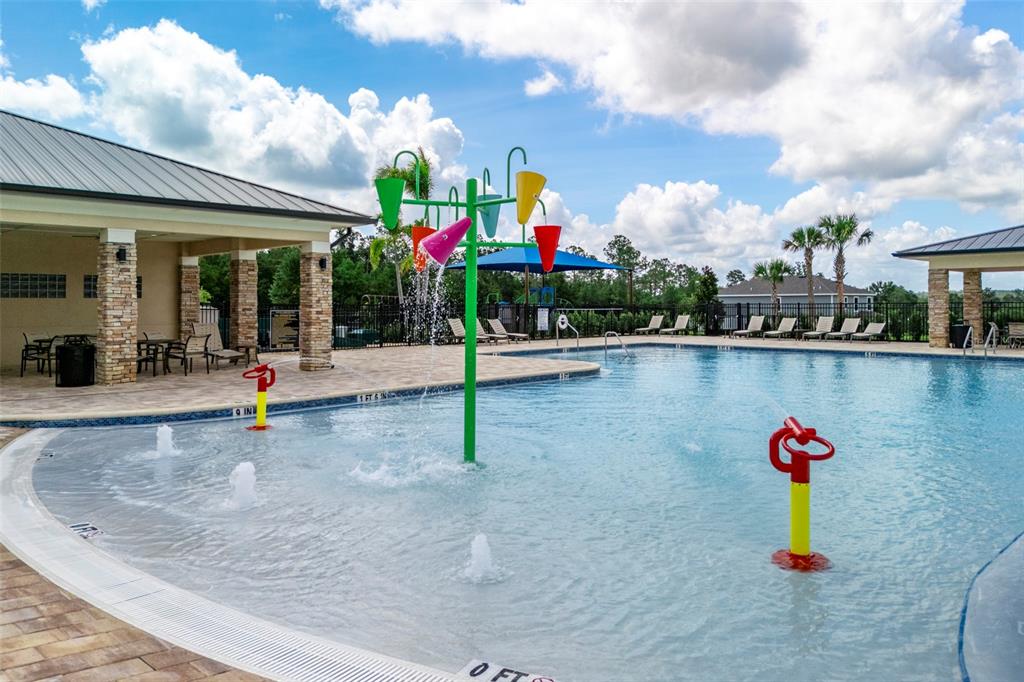A swimming pool with a splash pad feature and a covered patio area — 6812 BROAD WING LOOP, HOWEY IN THE HILLS, FL