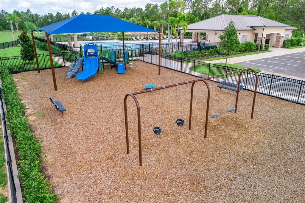 An outdoor playground features a blue shade structure, a slide, and a swing set — 6812 BROAD WING LOOP, HOWEY IN THE HILLS, FL