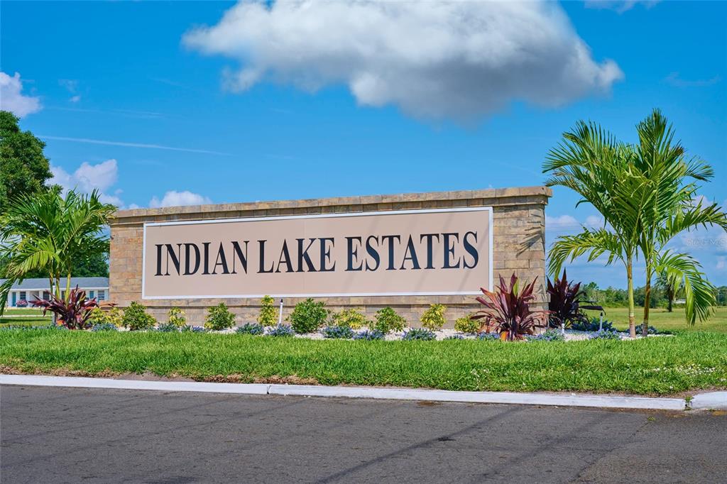 A stone monument sign for Indian Lake Estates stands in a grassy area with palm trees — 1022 CALLIANDRA DRIVE, INDIAN LAKE ESTATES, FL