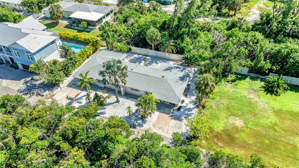 An aerial view shows a single-story house with a gray roof surrounded by lush vegetation — 578 - 580 COMPANION WAY, LONGBOAT KEY, FL