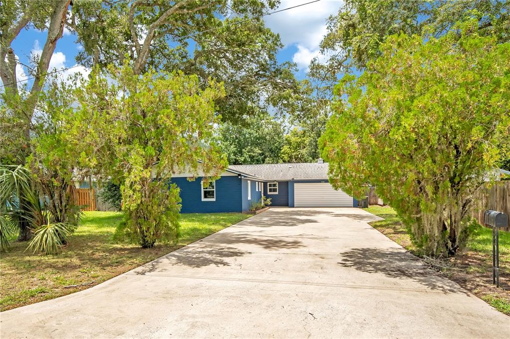 A blue single-story house with a white garage door and a long concrete driveway — 236 MCINTOSH ROAD, ORMOND BEACH, FL