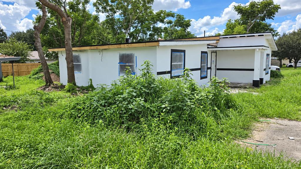 An unfinished room with exposed ceiling joists, light green walls, and a red exterior door — 1024 W FAIRBANKS AVENUE, ORLANDO, FL